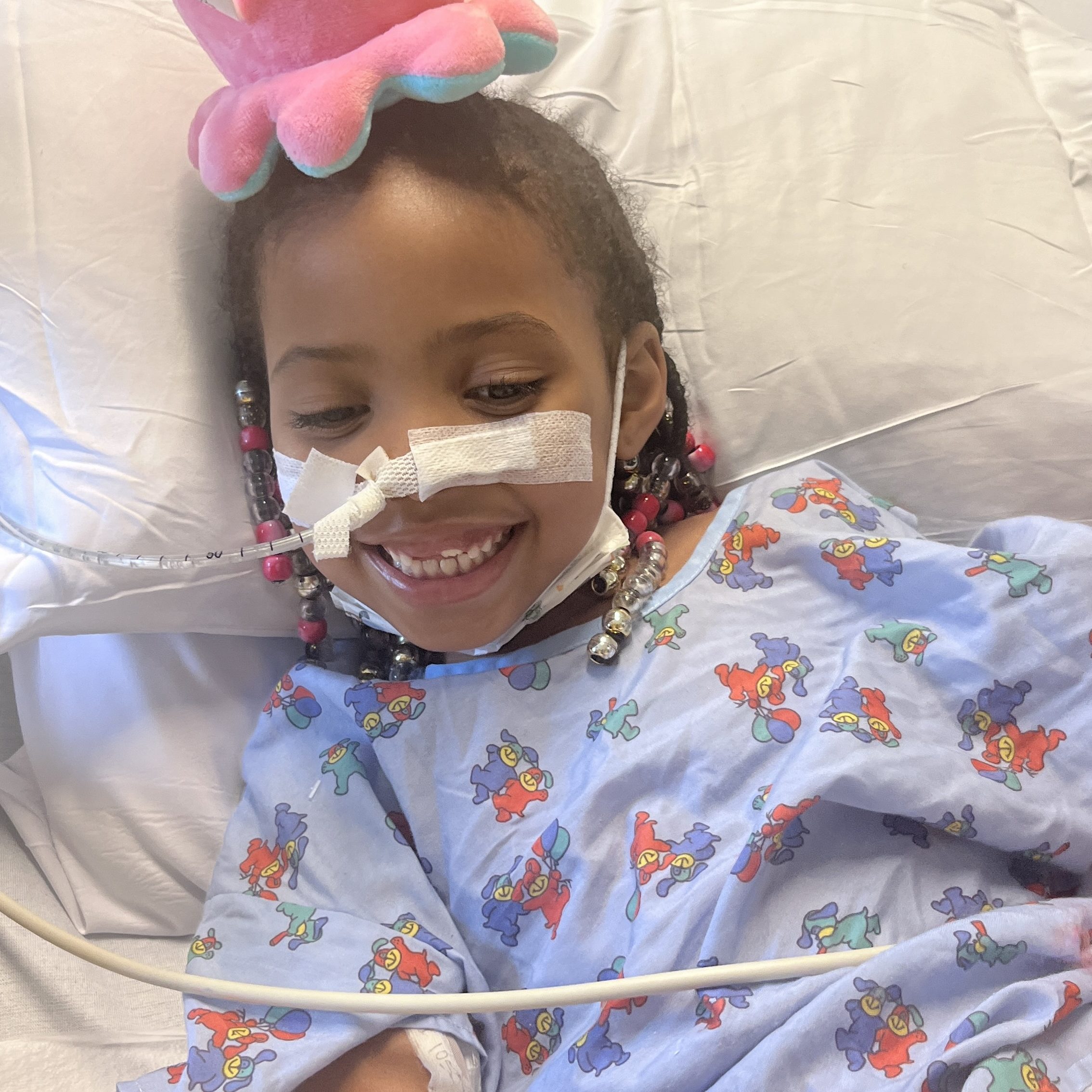 Little girl in hospital bed with NG tube and stuffed animal on her head